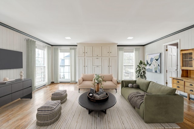 living room featuring ornamental molding, light wood-type flooring, and a healthy amount of sunlight