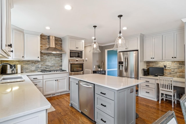 kitchen featuring wood finished floors, stainless steel appliances, wall chimney range hood, and a sink