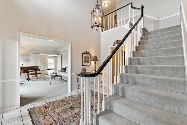 stairs with crown molding, carpet flooring, a chandelier, tile patterned flooring, and baseboards