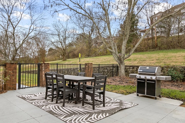 view of patio featuring a gate, fence, grilling area, and outdoor dining space