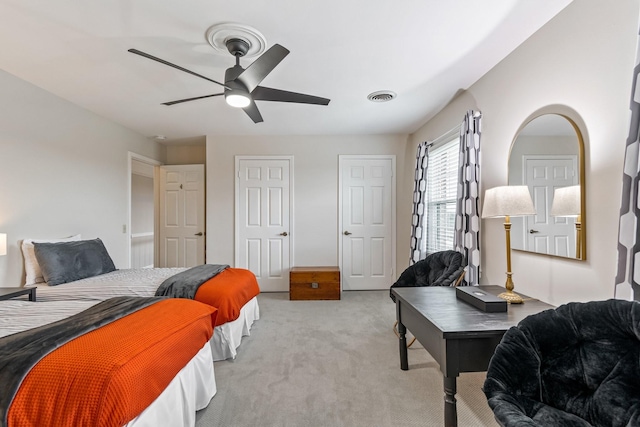 bedroom with light carpet, visible vents, and a ceiling fan