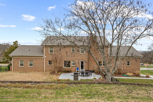 rear view of property with brick siding, a patio, a lawn, and fence