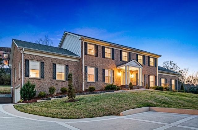 colonial inspired home featuring a yard and brick siding