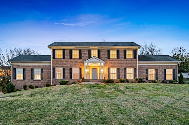 colonial house with a front lawn and brick siding