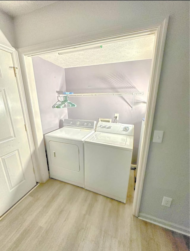 washroom with a textured ceiling, laundry area, light wood-type flooring, and independent washer and dryer