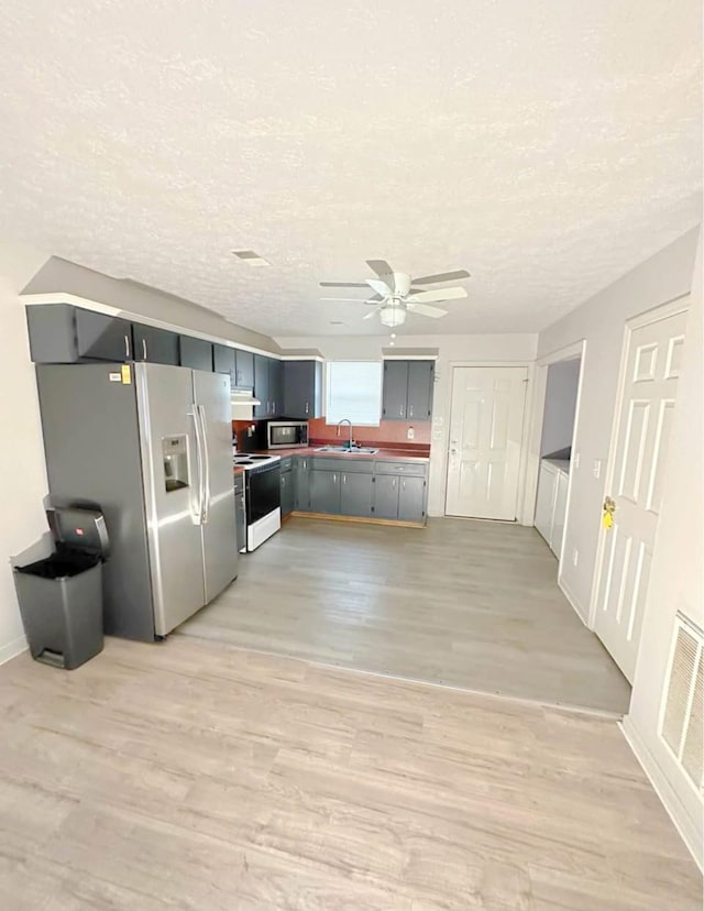 kitchen with visible vents, appliances with stainless steel finishes, a textured ceiling, light wood-style floors, and a sink