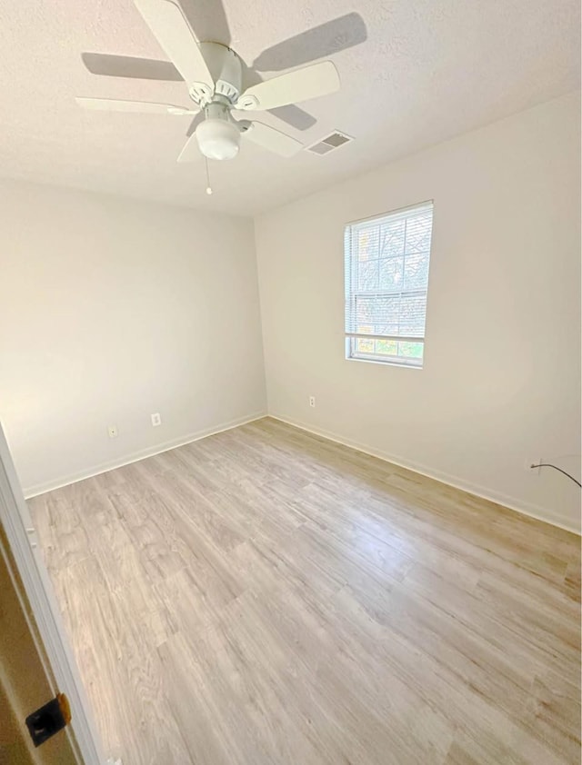 unfurnished room with light wood finished floors, visible vents, ceiling fan, a textured ceiling, and baseboards