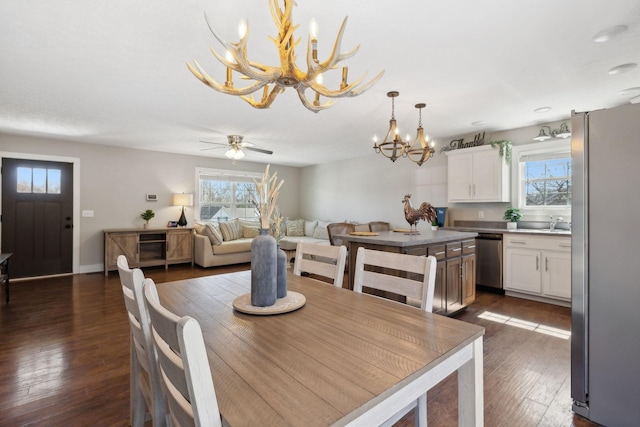 dining space featuring baseboards, dark wood finished floors, and ceiling fan with notable chandelier