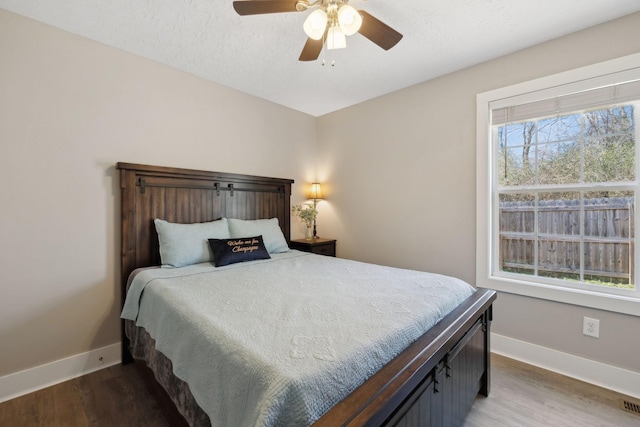 bedroom with a textured ceiling, wood finished floors, a ceiling fan, and baseboards