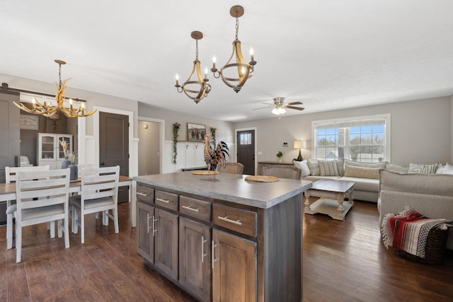 kitchen featuring a center island, open floor plan, decorative light fixtures, and dark wood finished floors