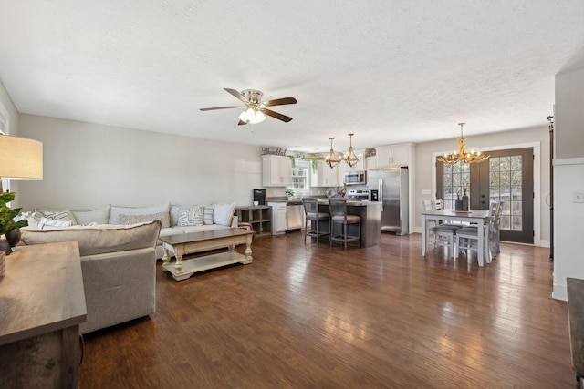 living room with dark wood-style floors, a textured ceiling, and ceiling fan with notable chandelier