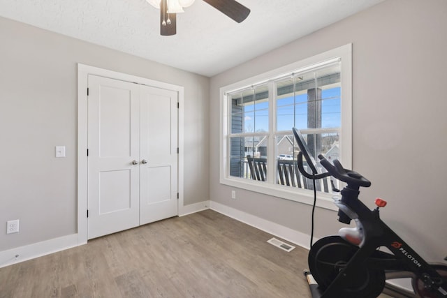 workout room with visible vents, baseboards, a ceiling fan, wood finished floors, and a textured ceiling