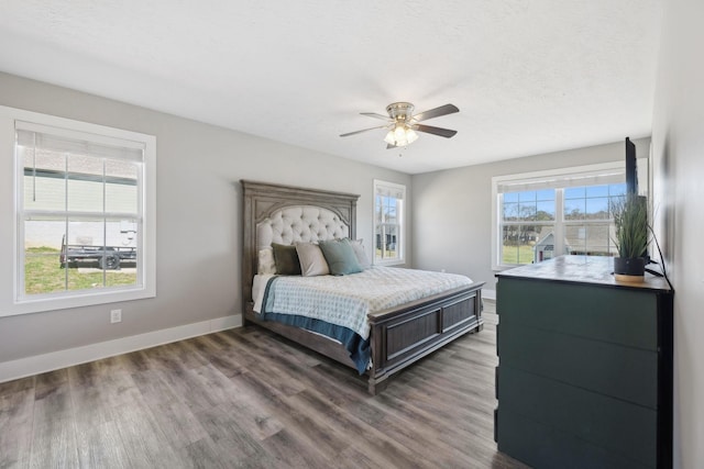 bedroom featuring ceiling fan, a textured ceiling, baseboards, and wood finished floors