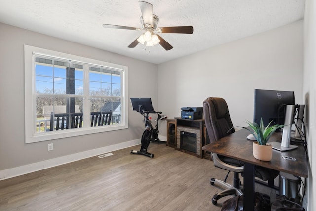 office featuring baseboards, visible vents, ceiling fan, wood finished floors, and a textured ceiling