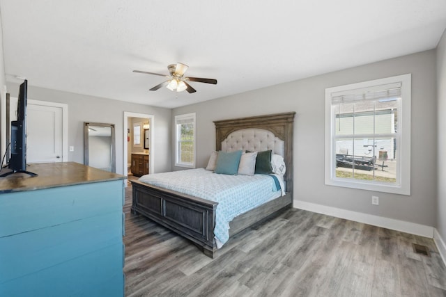 bedroom featuring multiple windows, wood finished floors, visible vents, and baseboards