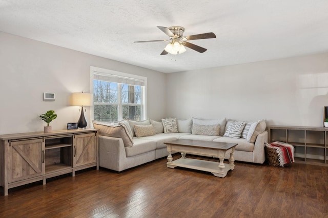 living area with a textured ceiling, ceiling fan, and dark wood-type flooring