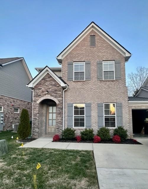 traditional-style house featuring concrete driveway, brick siding, and a front yard