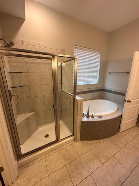 bathroom with a shower stall, a bath, and tile patterned floors