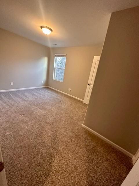 unfurnished room with dark carpet and baseboards