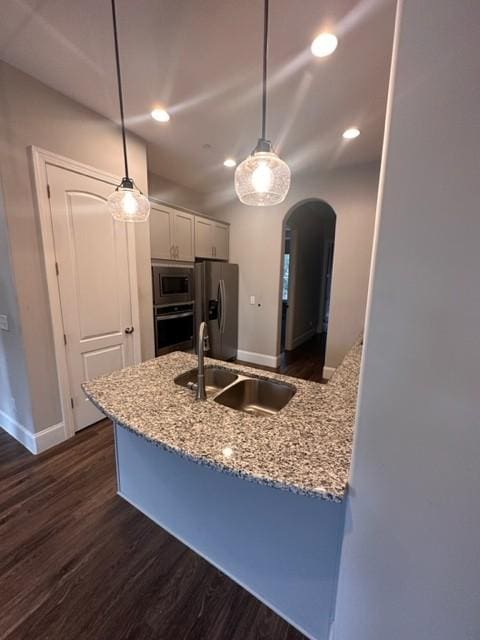 kitchen featuring arched walkways, white cabinets, dark wood-style floors, appliances with stainless steel finishes, and a sink