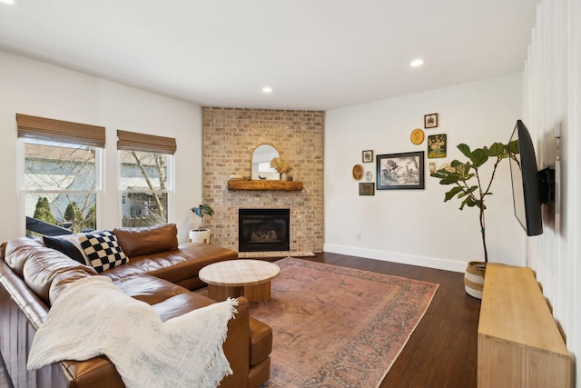 living room with recessed lighting, dark wood-style flooring, a brick fireplace, and baseboards