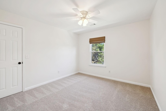 empty room with baseboards, ceiling fan, visible vents, and light colored carpet