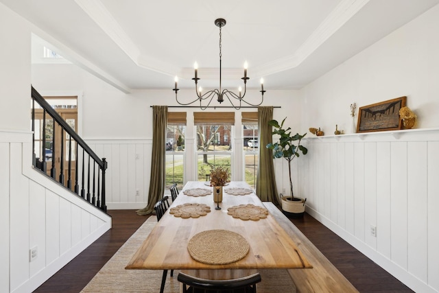 dining area with a raised ceiling, wainscoting, dark wood-style floors, stairway, and a chandelier