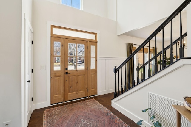 entryway with stairs, a wainscoted wall, visible vents, and wood finished floors