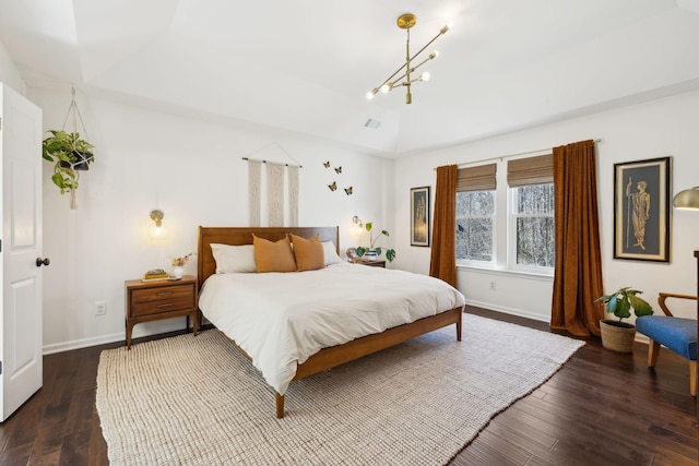 bedroom with dark wood-type flooring, a chandelier, a raised ceiling, and baseboards