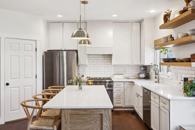 kitchen with appliances with stainless steel finishes, dark wood-style flooring, light countertops, open shelves, and a sink