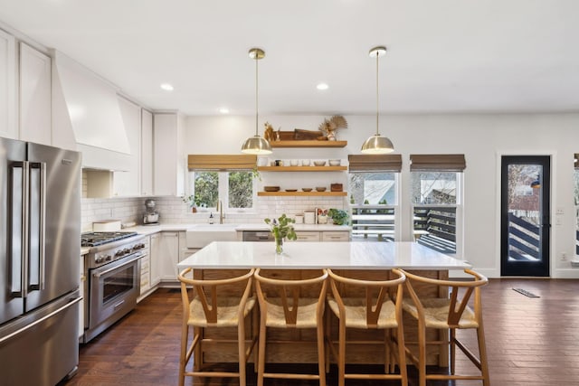 kitchen featuring decorative backsplash, light countertops, a kitchen breakfast bar, and high quality appliances