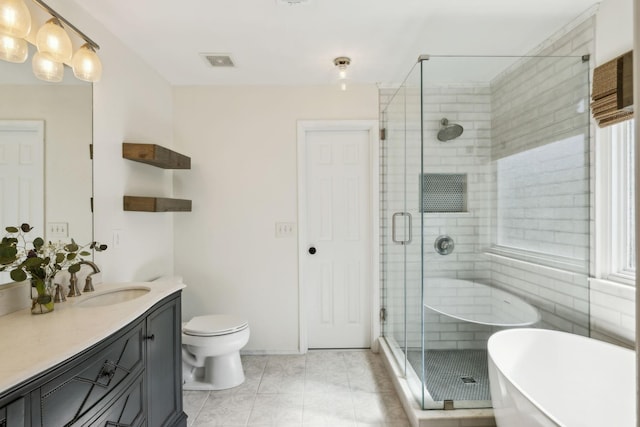 bathroom with a freestanding bath, toilet, vanity, a shower stall, and tile patterned flooring