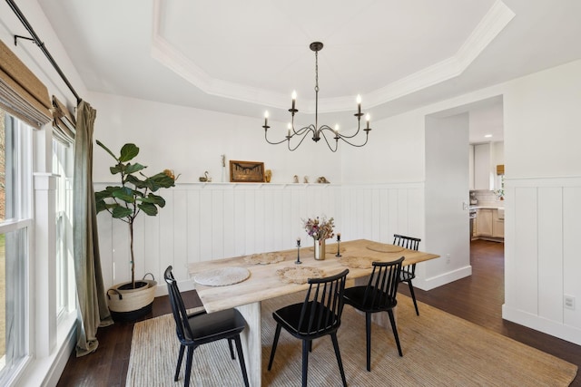 dining space with a tray ceiling, dark wood-style flooring, wainscoting, and crown molding