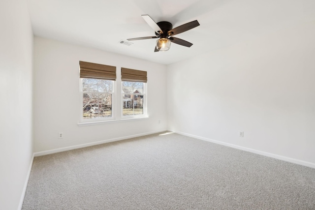 carpeted spare room with baseboards, visible vents, and ceiling fan