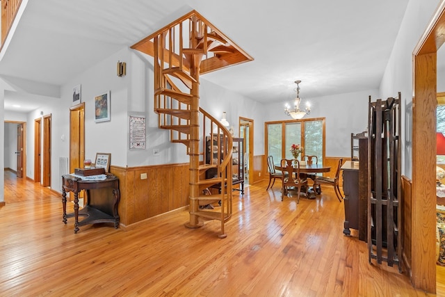 interior space with wood-type flooring, wainscoting, a notable chandelier, and wooden walls