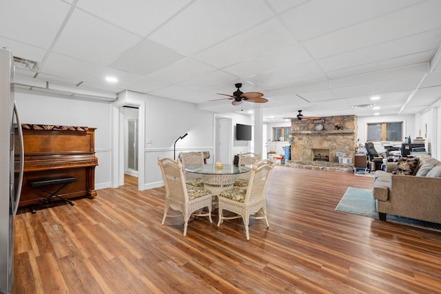 dining area with a fireplace, wood finished floors, a paneled ceiling, and a ceiling fan