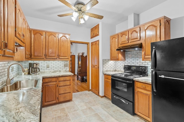 kitchen with brown cabinets, backsplash, a sink, under cabinet range hood, and black appliances