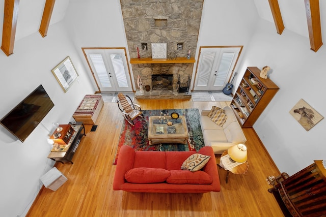 living room featuring french doors, a fireplace, wood finished floors, high vaulted ceiling, and beamed ceiling