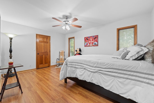 bedroom featuring a ceiling fan, baseboards, and light wood finished floors