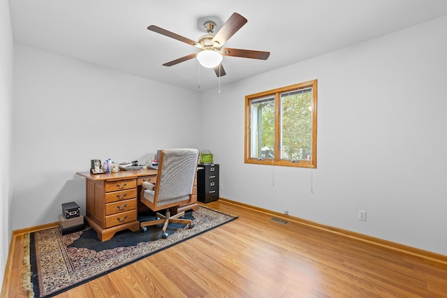 home office with visible vents, ceiling fan, baseboards, and wood finished floors