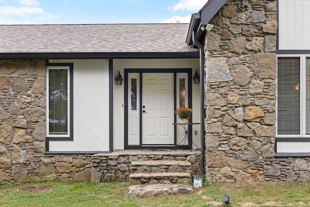 doorway to property with stone siding and roof with shingles