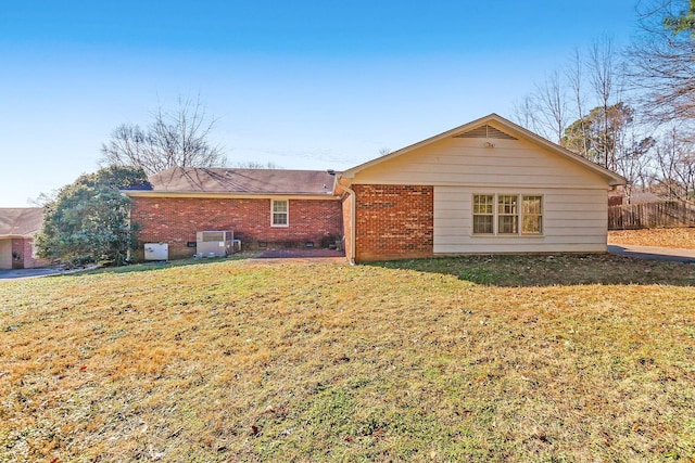 back of property featuring a yard, brick siding, and fence