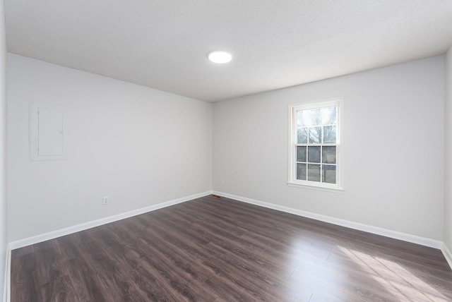 unfurnished room with electric panel, dark wood finished floors, and baseboards