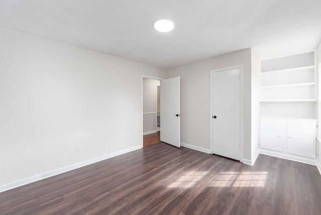 unfurnished bedroom with dark wood finished floors and baseboards