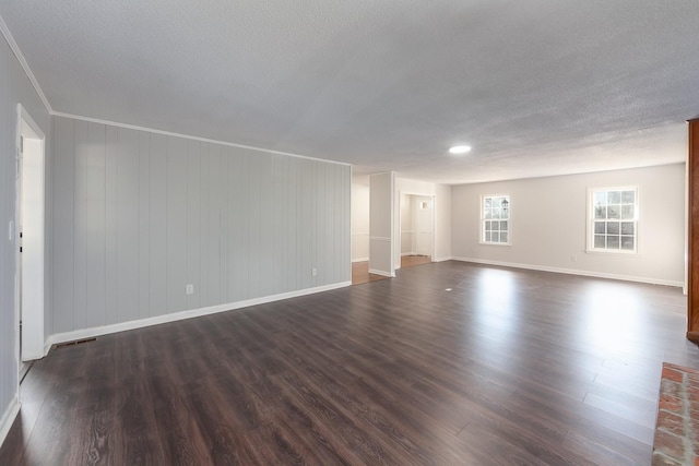 spare room featuring visible vents, dark wood finished floors, a textured ceiling, and baseboards