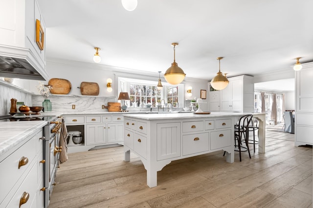 kitchen with plenty of natural light, double oven range, white cabinetry, and a center island