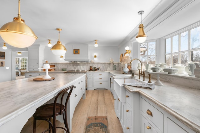 kitchen with light wood-type flooring, plenty of natural light, backsplash, and white cabinetry