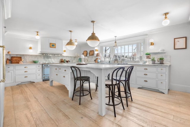 kitchen with a center island, a breakfast bar area, tasteful backsplash, white cabinets, and light wood-type flooring