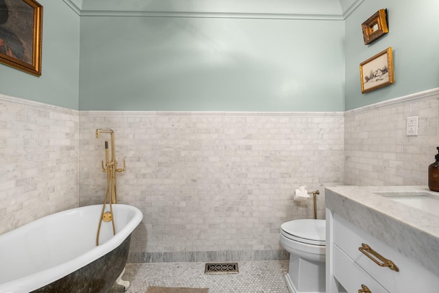 bathroom featuring a soaking tub, wainscoting, tile walls, and toilet