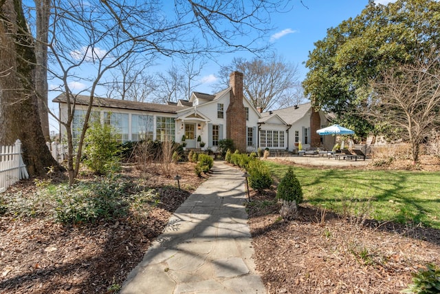 view of front of home featuring a patio, a chimney, a front yard, and fence